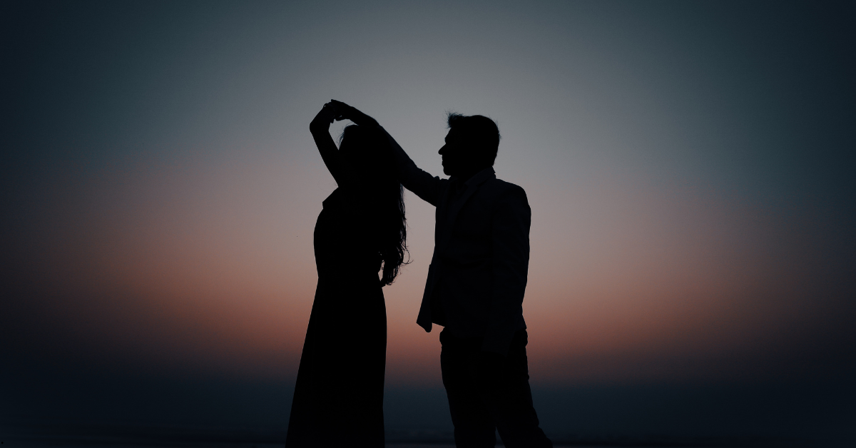 Casal em conexão íntima e leveza após a chegada do bebê Casal dançando em silhueta ao pôr do sol