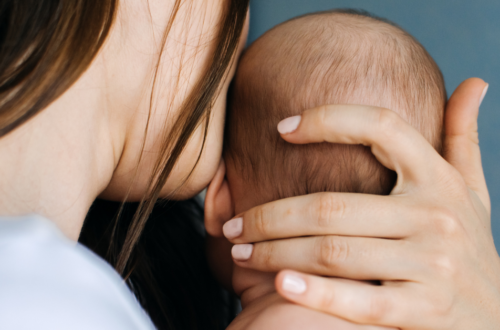Mãe segurando o bebê com carinho enquanto olha para baixo, demonstrando emoção