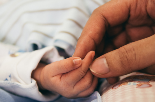 Mãe segurando delicadamente a mão do bebê recém-nascido