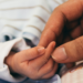 Mãe segurando delicadamente a mão do bebê recém-nascido