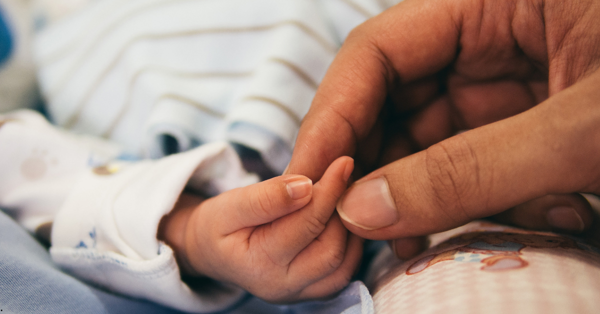 Mãe e bebê segurando as mãos com delicadeza Mãe segurando delicadamente a mão do bebê recém-nascido