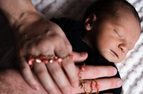 Bebê dormindo durante a regressão do sono, com mãos adultas oferecendo conforto e acolhimento